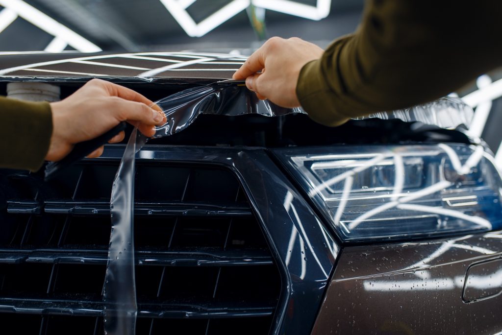 Worker cuts protection film on car hood